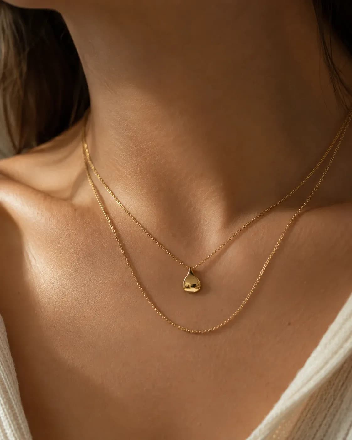 Layered gold necklace worn on a model's collarbone
