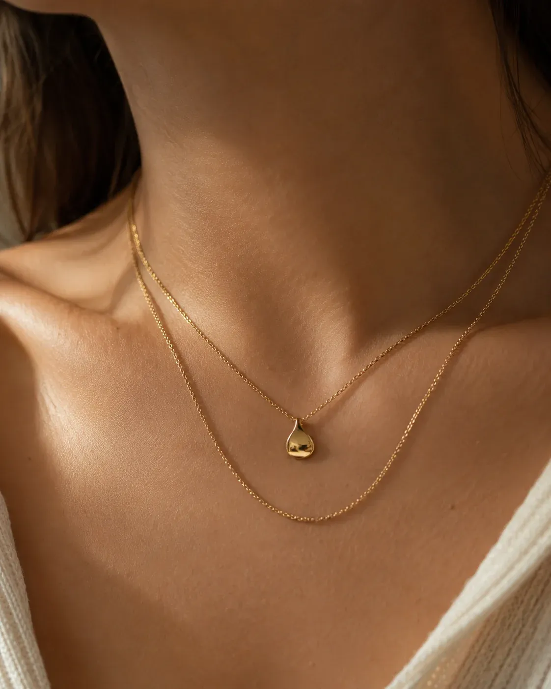 Layered gold necklace worn on a model's collarbone